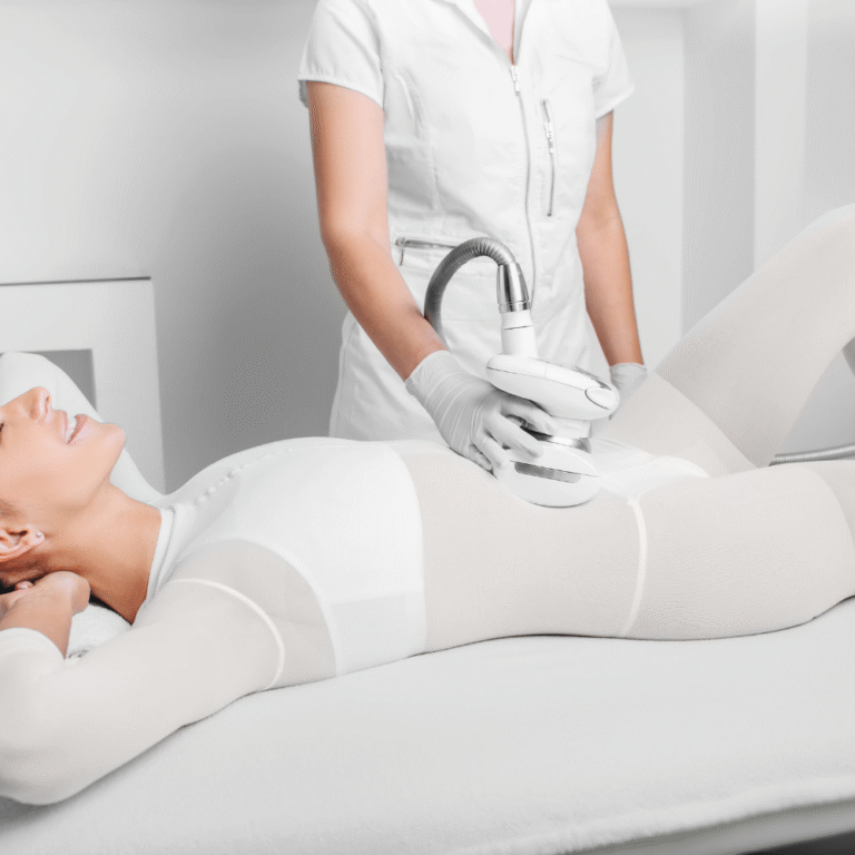 A therapist performs an LPG endermologie treatment on a client's abdomen using a roller handpiece over a white treatment suit.