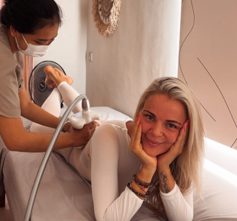 A therapist guides an LPG endermologie handpiece up the back of a client's leg; she wears the white suit the machine works through.