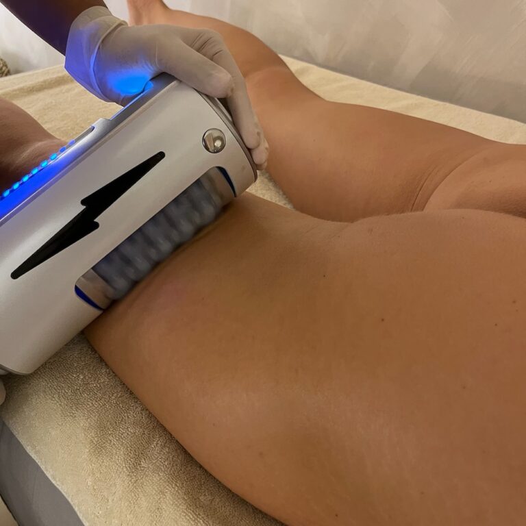 A therapist uses an Endospheres roller handpiece on a client’s thigh and hip.