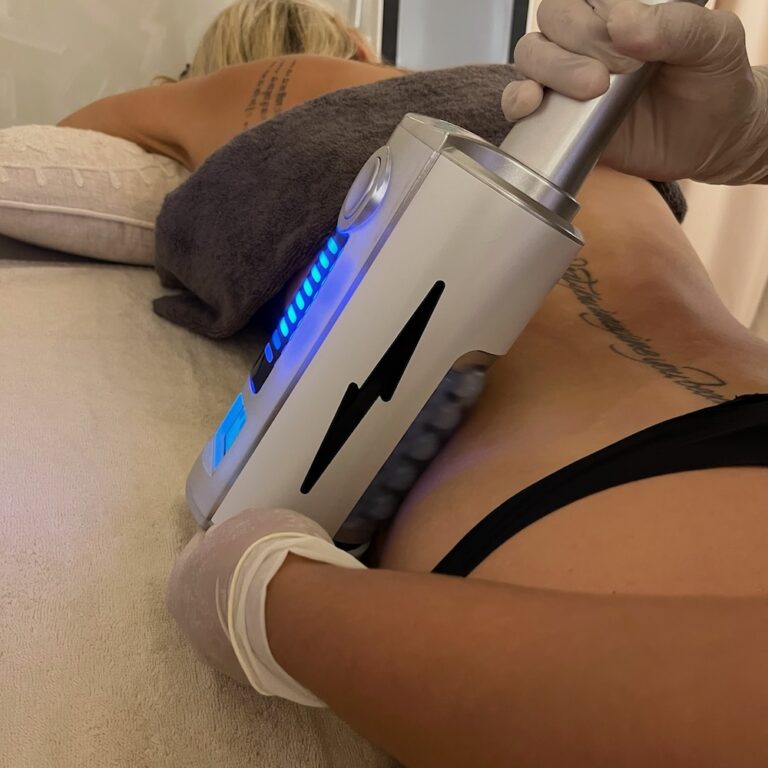 A therapist uses an Endospheres roller handpiece on a client's abdomen.
