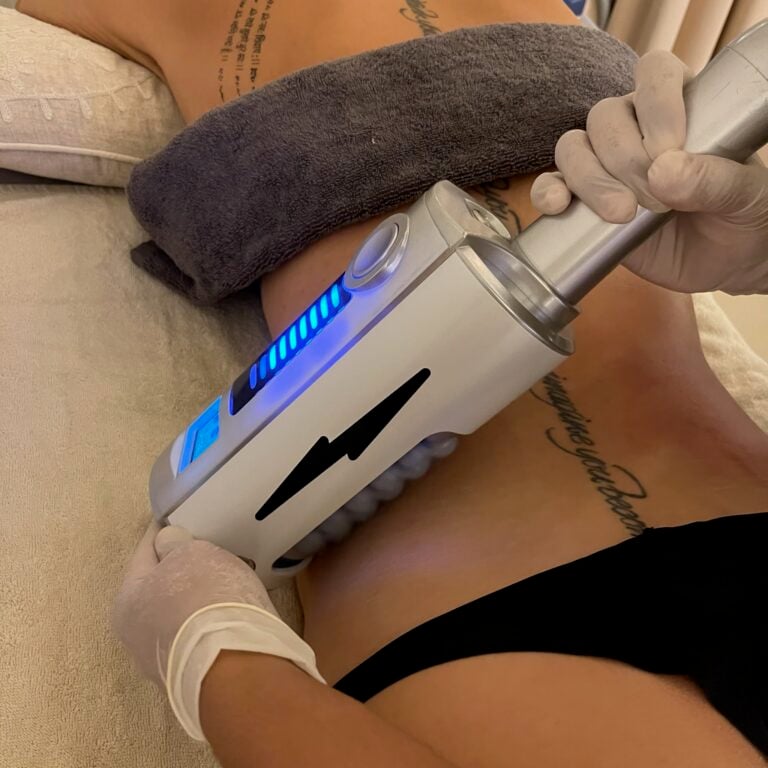 A therapist uses an Endospheres roller handpiece on a client's abdomen.