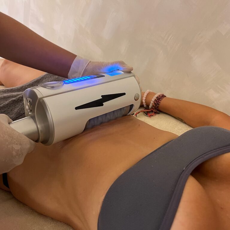 A therapist uses an Endospheres roller handpiece on a client's abdomen.