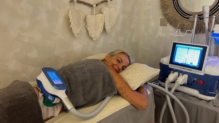 A client receives cryolipolysis treatment with a clamped applicator positioned on her abdomen.