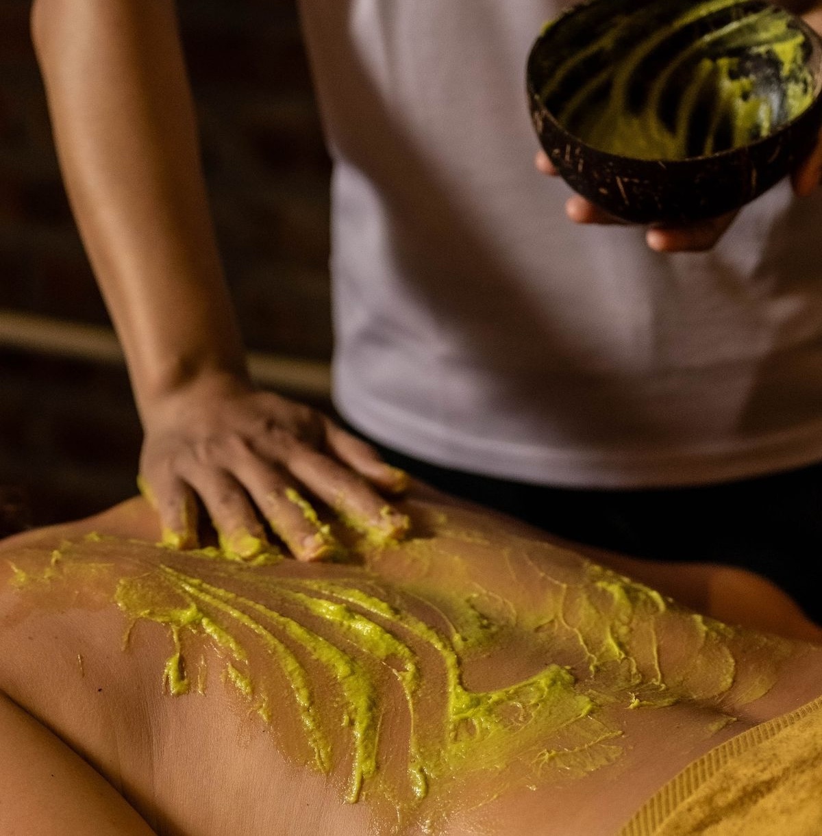 A therapist's hand applies a traditional herbal treatment by hand.