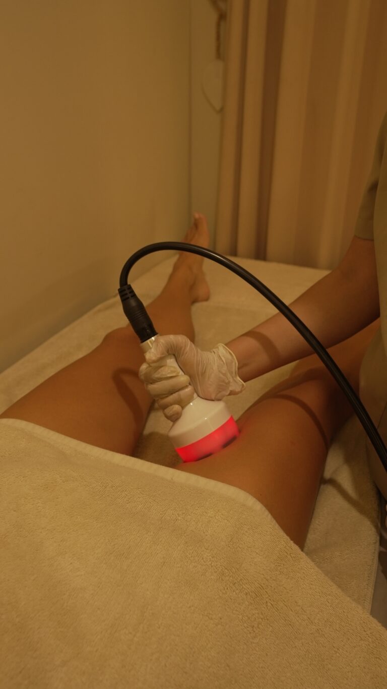 A practitioner applies a handheld radiofrequency probe to a client's upper thigh.