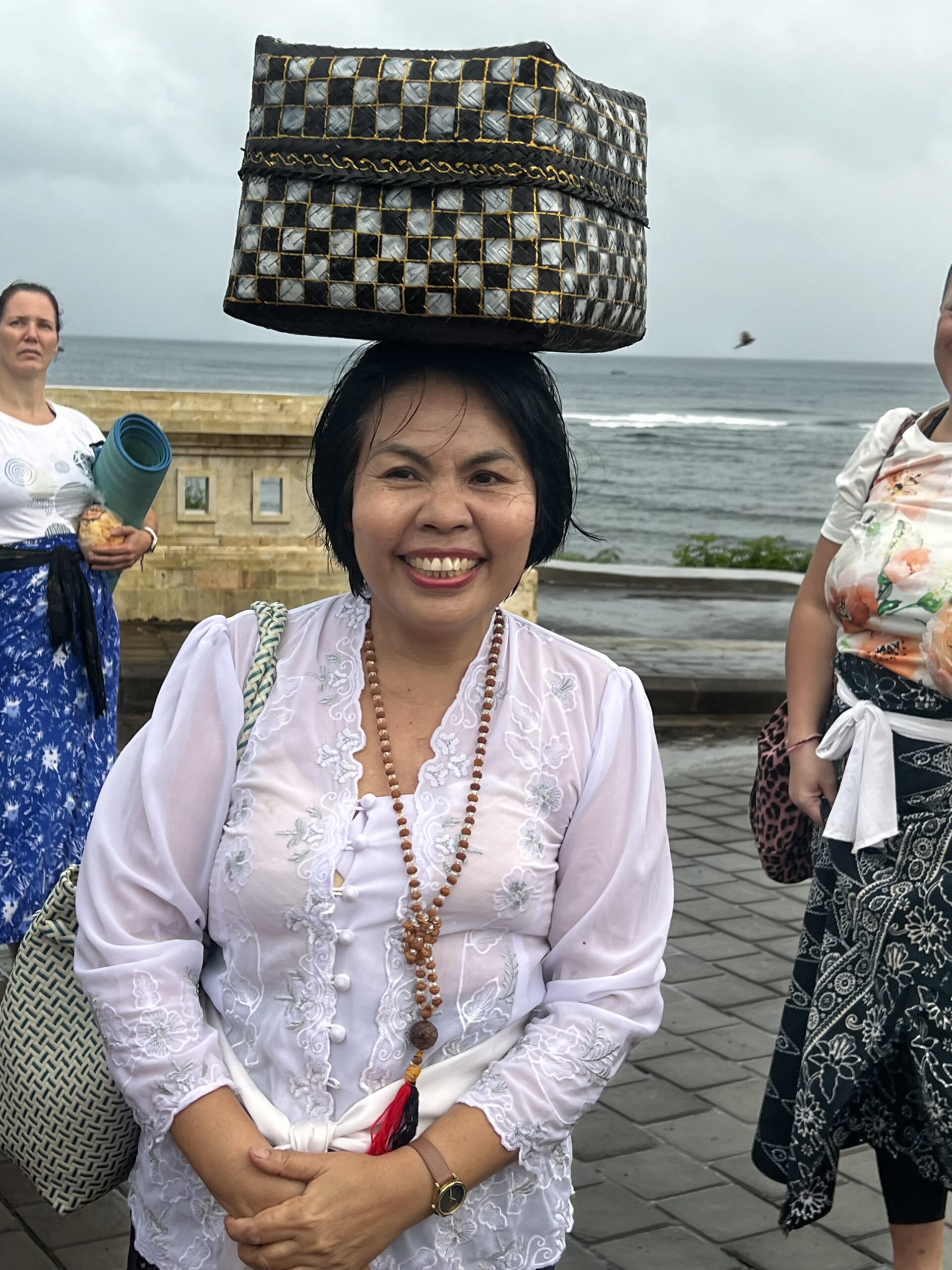 Jero Kartini in ceremonial white, carrying a traditional woven offering basket