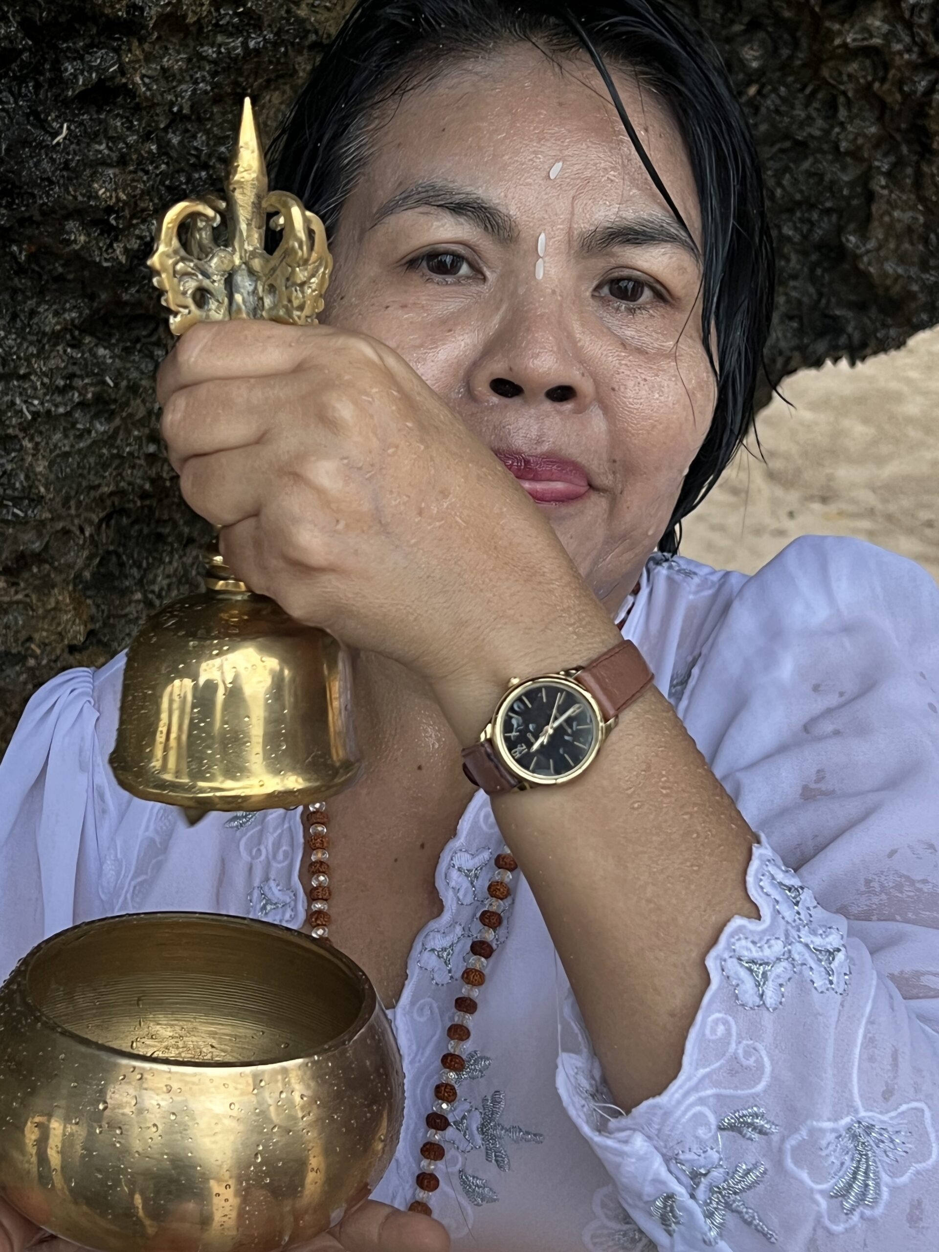 Jero Kartini holds a ceremonial bell and holy water bowl during a purification ritual